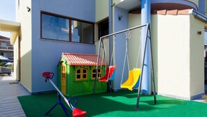 Un espace de jeux pour enfants avec des balançoires et une petite maison de jeu.