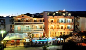 A multi-story hotel with balconies, a swimming pool, and a covered outdoor area.