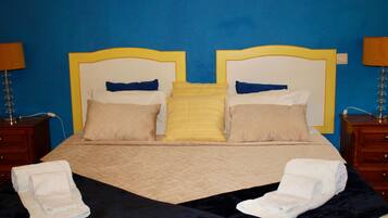 A bed with a quilted cover, two bedside tables with lamps, and towels on the bed.