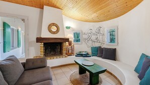 Een woonkamer met een open haard, een bank, een bijzettafeltje en een gebogen witte bank.