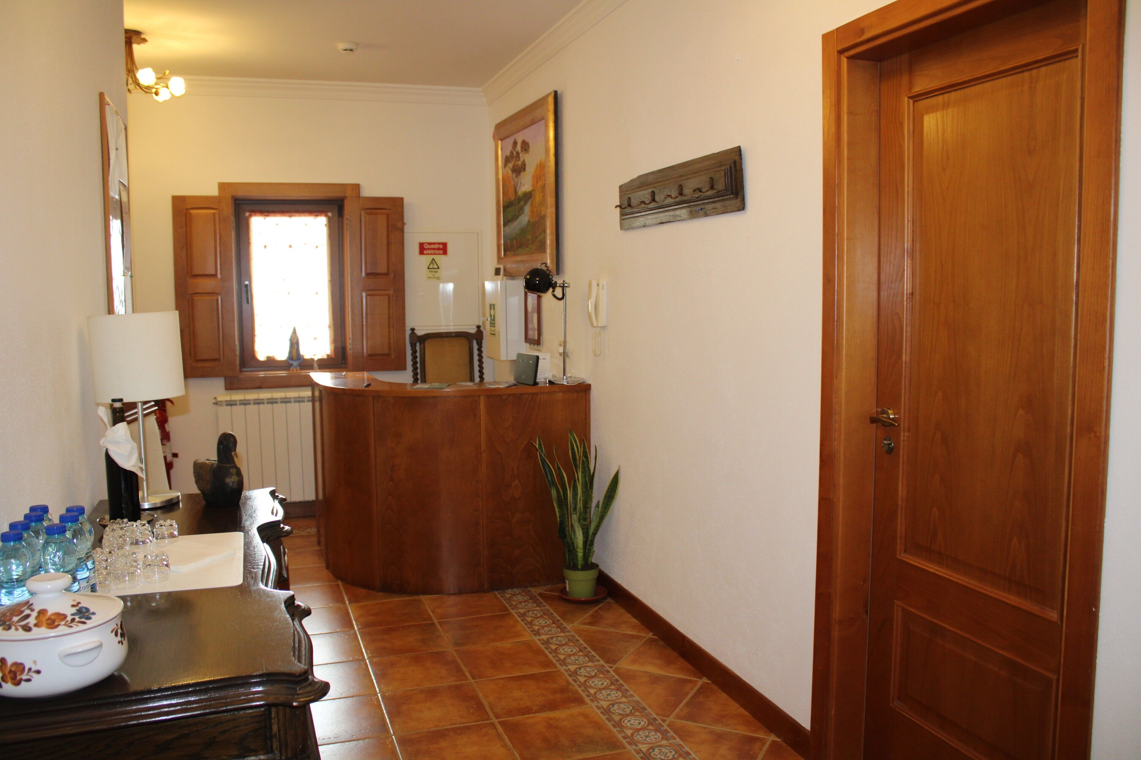 Una cocina con armarios de madera, suelo de baldosas, una planta en maceta y una puerta.