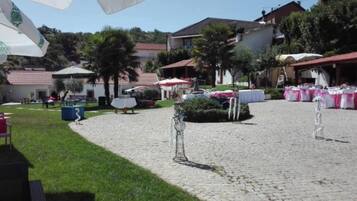 Een erf met geplaveid pad, buitentafels en parasols.