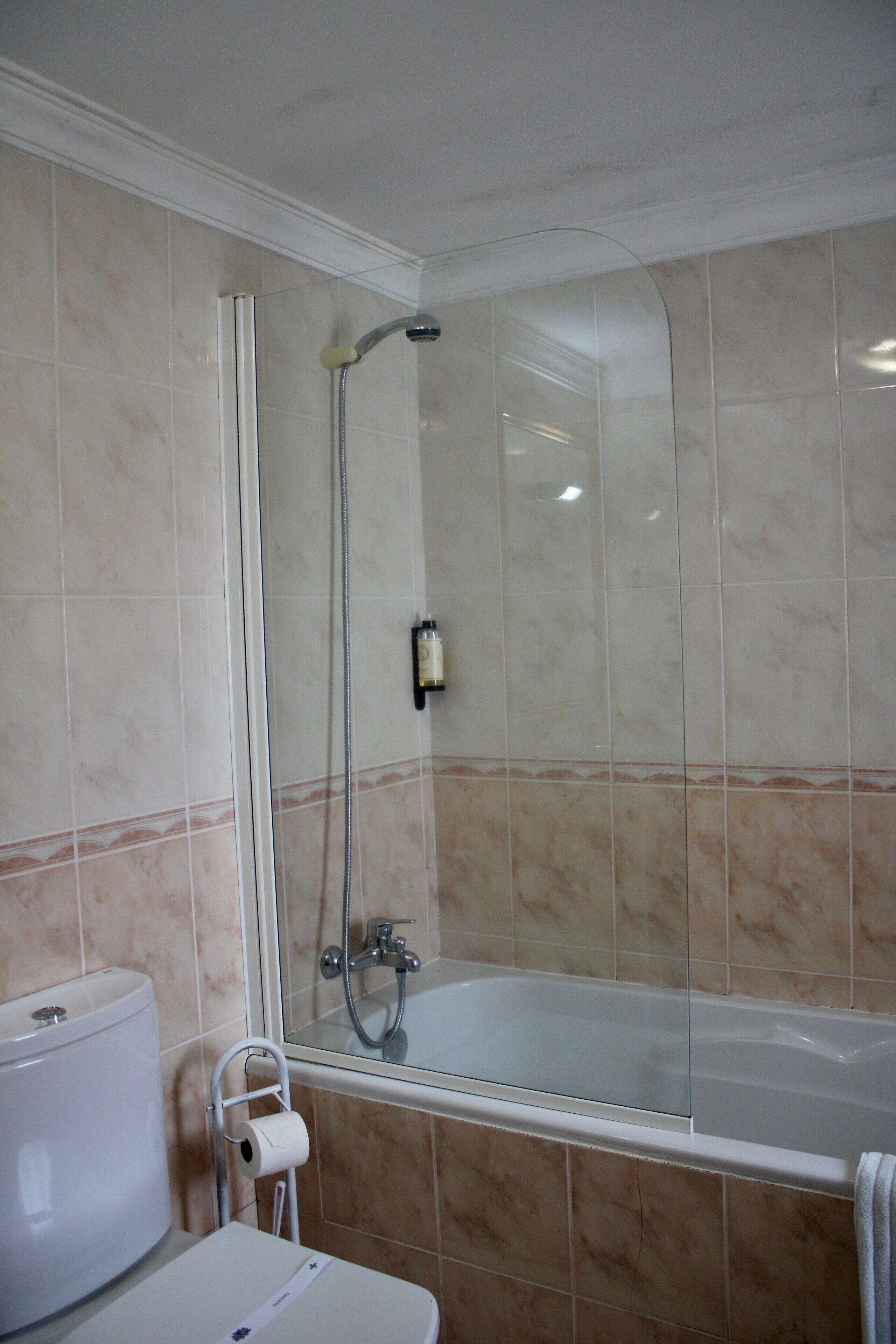 A bathroom with a bathtub, a toilet, and a shower enclosure.