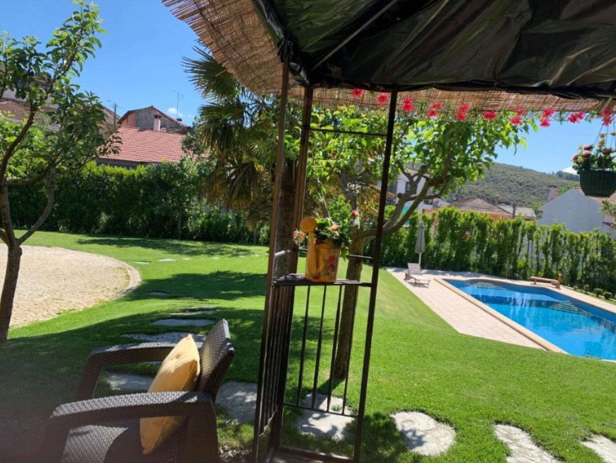A poolside area with a covered seating area, a pool, and a well-maintained lawn.