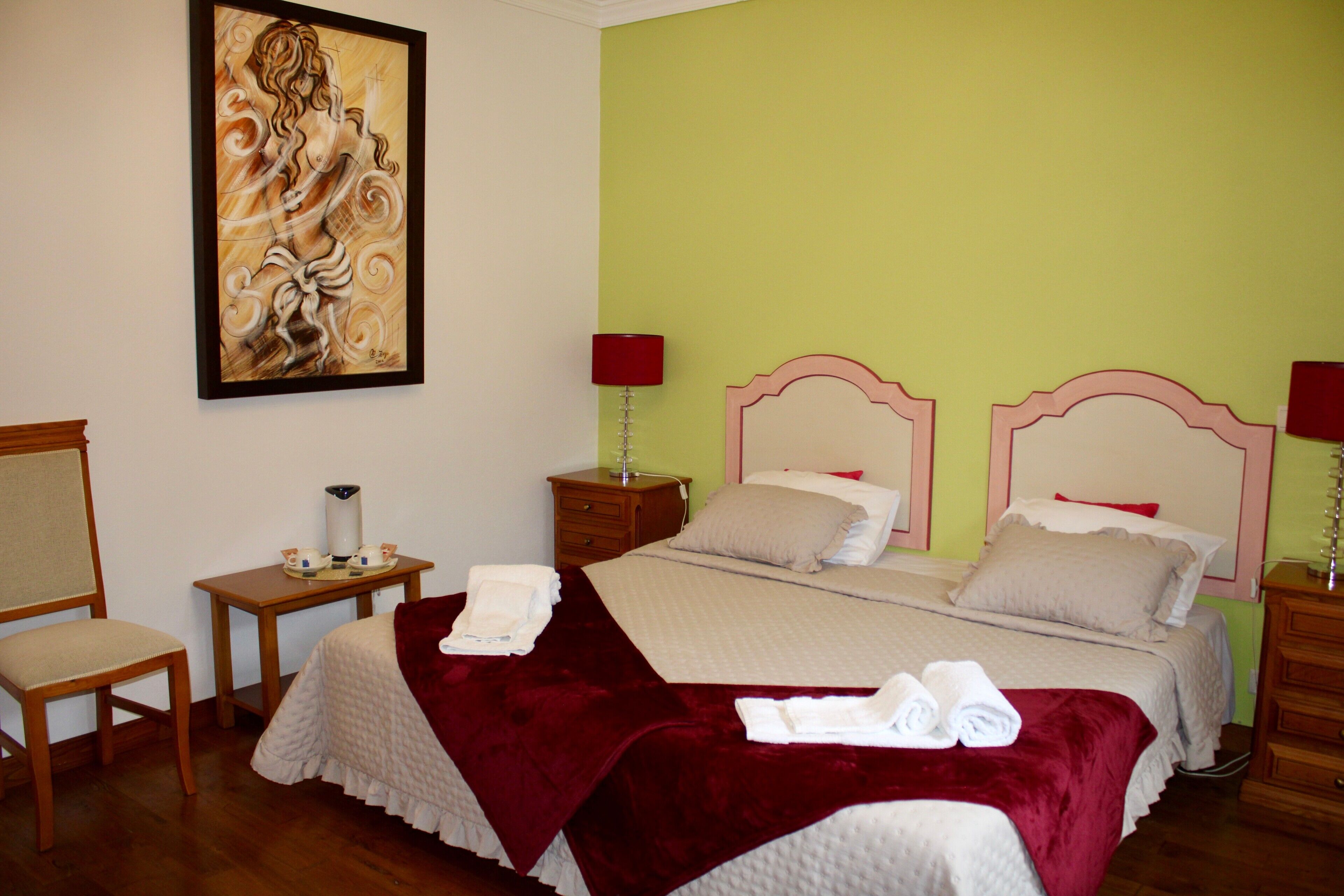 Hotelkamer met een bed, twee nachtkastjes, een stoel, een schilderij aan de muur en een lamp.