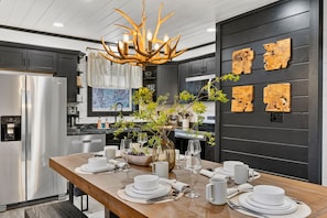 Una cocina moderna con una mesa de comedor de madera para seis personas, un refrigerador de acero inoxidable y una lámpara colgante original.
