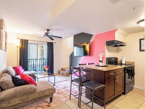 A compact living space with a kitchenette, a dining area, and a balcony with a view. - Disney Family Retreat-Pool & Walk to Target (Kissimmee)