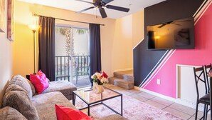 Una sala de estar con sofá, mesa de centro y televisor montado en la pared.