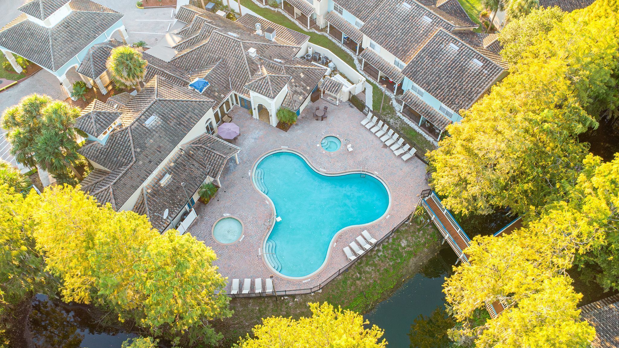 Un quartier résidentiel doté d’une piscine, de toits en tuiles et d’un feuillage jaune.