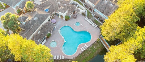 A residential area with a swimming pool, tiled roofs, and yellow foliage.