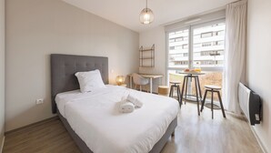 A modern hotel room with a large bed, a desk, and a small table with stools. - 1 Le Loki - Tramway - Wifi (Clermont-Ferrand)