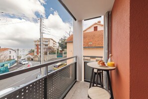 Ein Balkon mit Tisch, Stuhl und einer Orangensaftflasche.