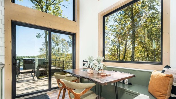 Een moderne eethoek met een houten tafel, twee stoelen en een bank.