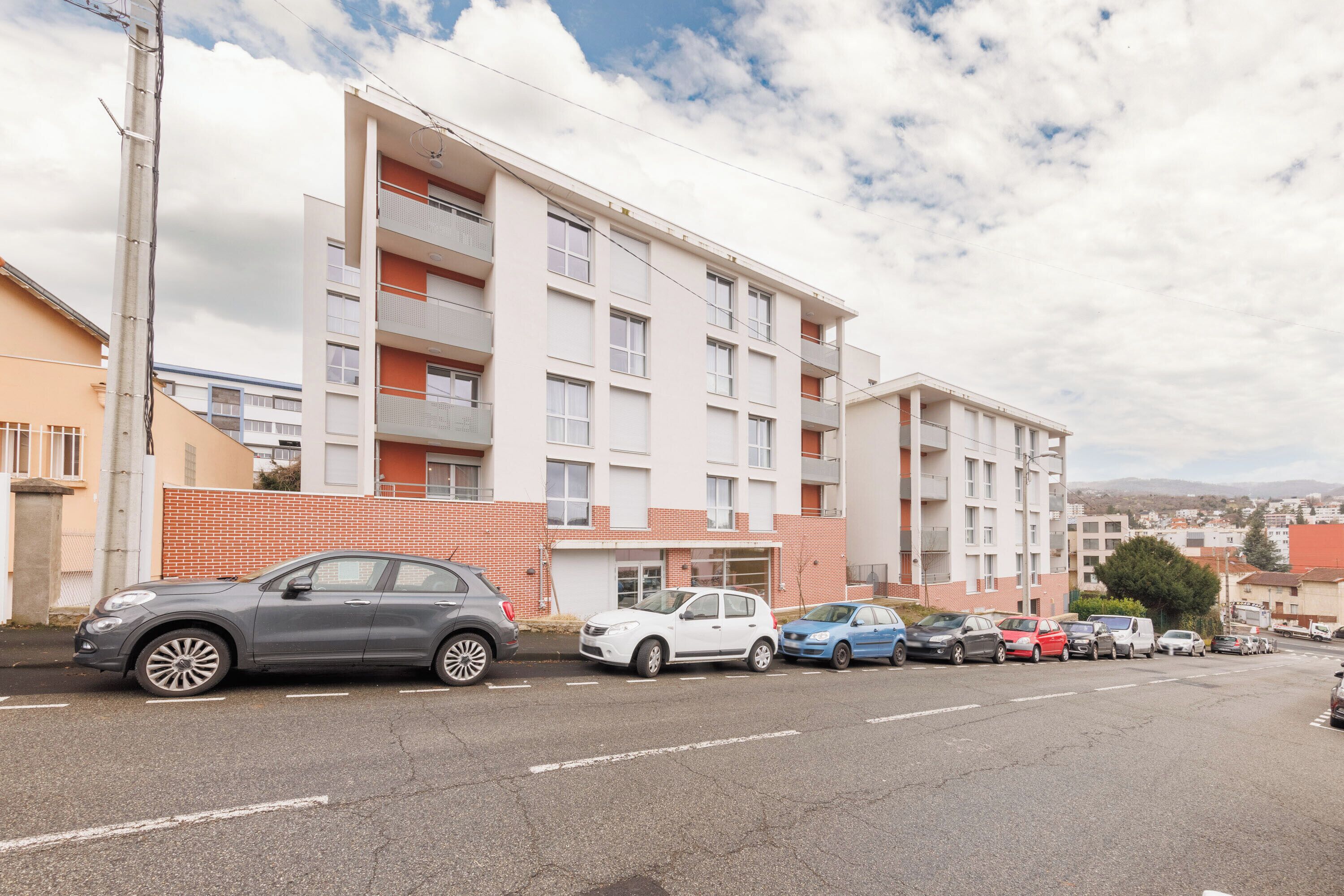 A multi-story residential building with a parking lot in front.