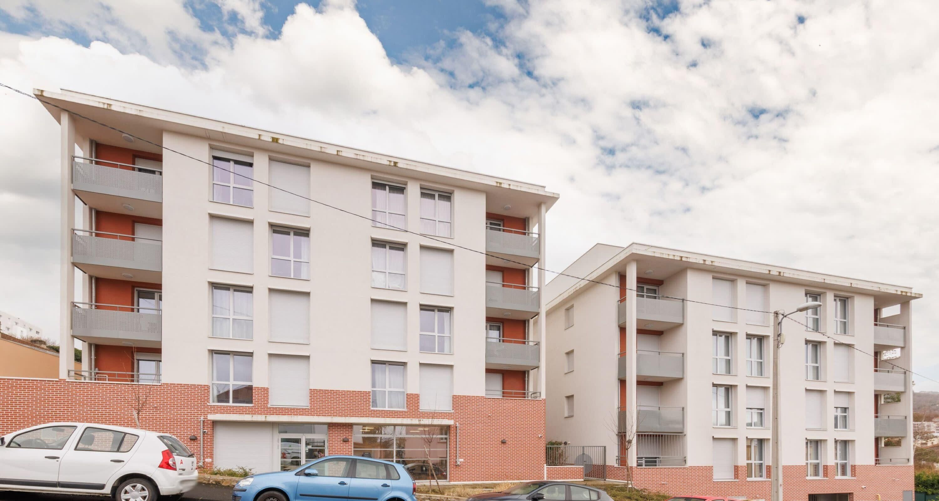 A modern apartment building with multiple balconies, a brick facade, and a clear sky.