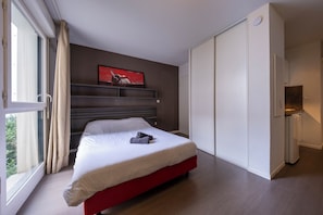 Une chambre à coucher moderne avec un lit, une armoire et une fenêtre avec des rideaux.