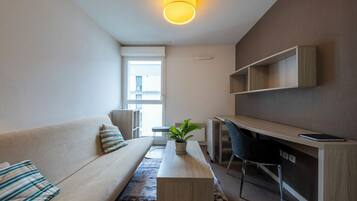 Ein modernes Wohnzimmer mit einer Couch, einem Couchtisch, einem Schreibtisch und einem Sessel.