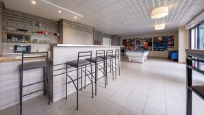 Moderni keittiö, jossa on baaritiski, biljardipöytä ja suuri ikkuna.