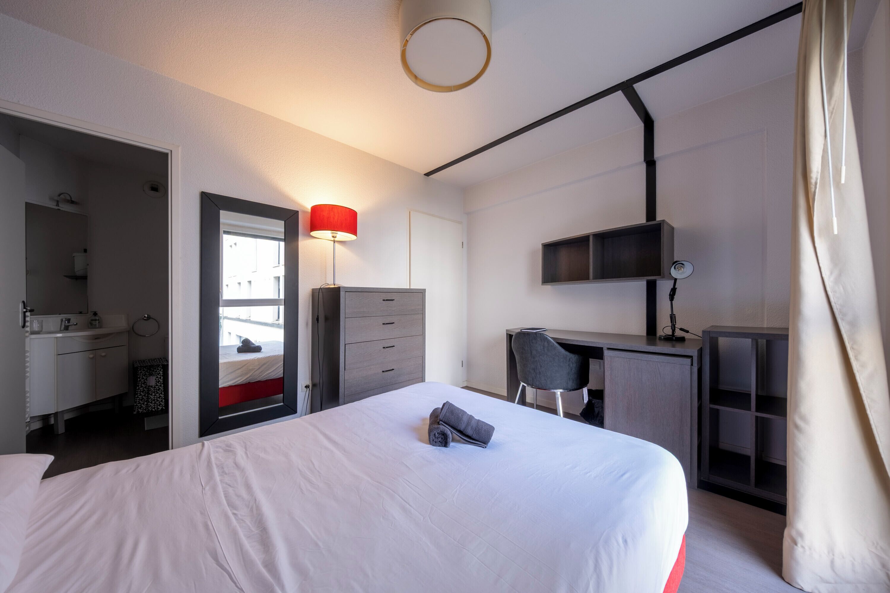Una habitación de hotel moderna con una cama grande, un escritorio, una silla y una televisión.