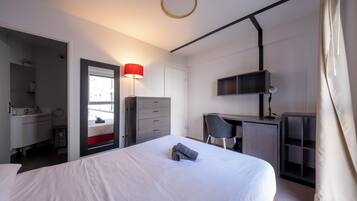 Una habitación de hotel moderna con una cama grande, un escritorio, una silla y una televisión.