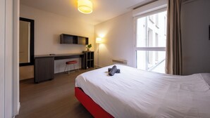 A hotel room with a bed, a desk, a chair, a lamp, and a window. - 1 - L'Envol - Gare - Wifi (Toulouse)