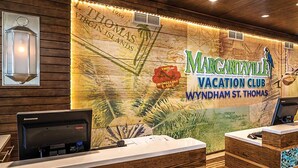Eine Rezeption mit einer Wandmalerei einer Karte, einem Computer und einem Schild für 'Margaritaville Vacation Club Wyndham St. Thomas'.
