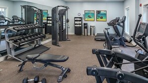 Ein Fitnessstudio mit Laufbändern, Crosstrainern, einer Gewichtbank und Kurzhanteln.