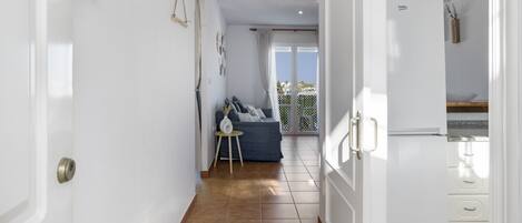 A hallway with a sofa, a small table, and a refrigerator.