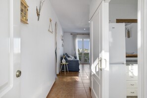 A hallway with a sofa, a small table, and a refrigerator. - Apartamento 'Casa Hinojal' con terraza privada, balcón y aire acondicionado (Conil de la Frontera)