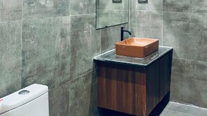 A bathroom with a rectangular sink on a dark wooden vanity, a mirror above the sink, and a toilet to the left.