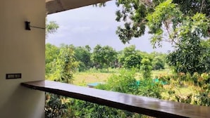 A balcony with a view of a lush garden and trees.