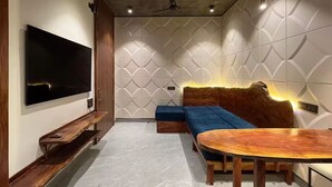 A modern living room with a flat-screen TV, a wooden bench, a blue sofa, and a wooden coffee table.