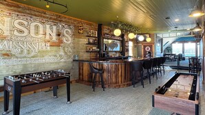 A bar area with a foosball table, a bar counter, and a seating area with chairs. - Cozy Gem With Stunning Mississippi River View (Albany)
