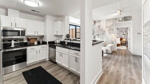A modern kitchen with white cabinetry, black countertops, and stainless steel appliances. - Solara – Luxury 1BR Downtown (Stamford)