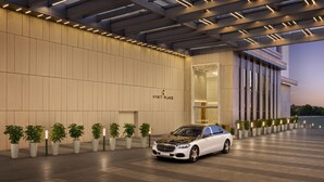 Un edificio moderno con il cartello 'HYATT PLACE', un'auto bianca e piante in vaso.