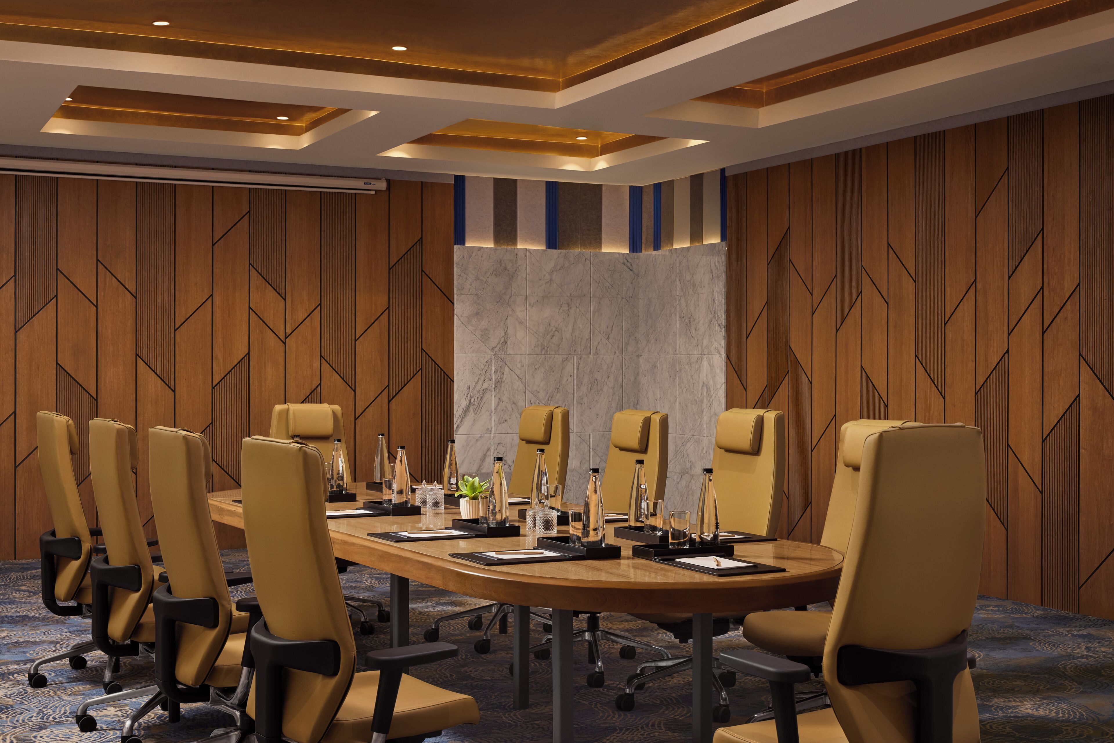 A conference room with a long table, multiple chairs, and a marble accent wall.