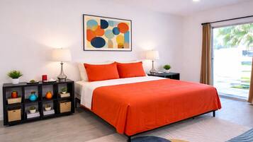 Un dormitorio moderno con cama, dos mesitas de noche, una lámpara de noche, un cuadro en la pared y vistas al exterior.