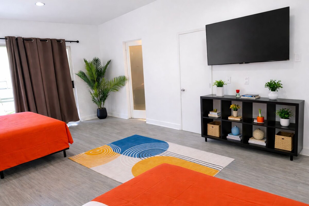 Une chambre d’hôtel avec deux lits, une télévision, une bibliothèque et une plante en pot.