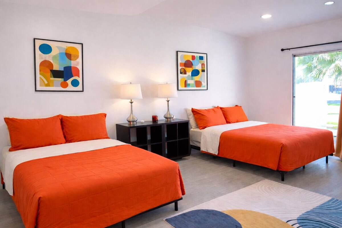 Une chambre d’hôtel avec deux lits, une table de chevet, deux lampes et des œuvres d’art abstraites accrochées aux murs.