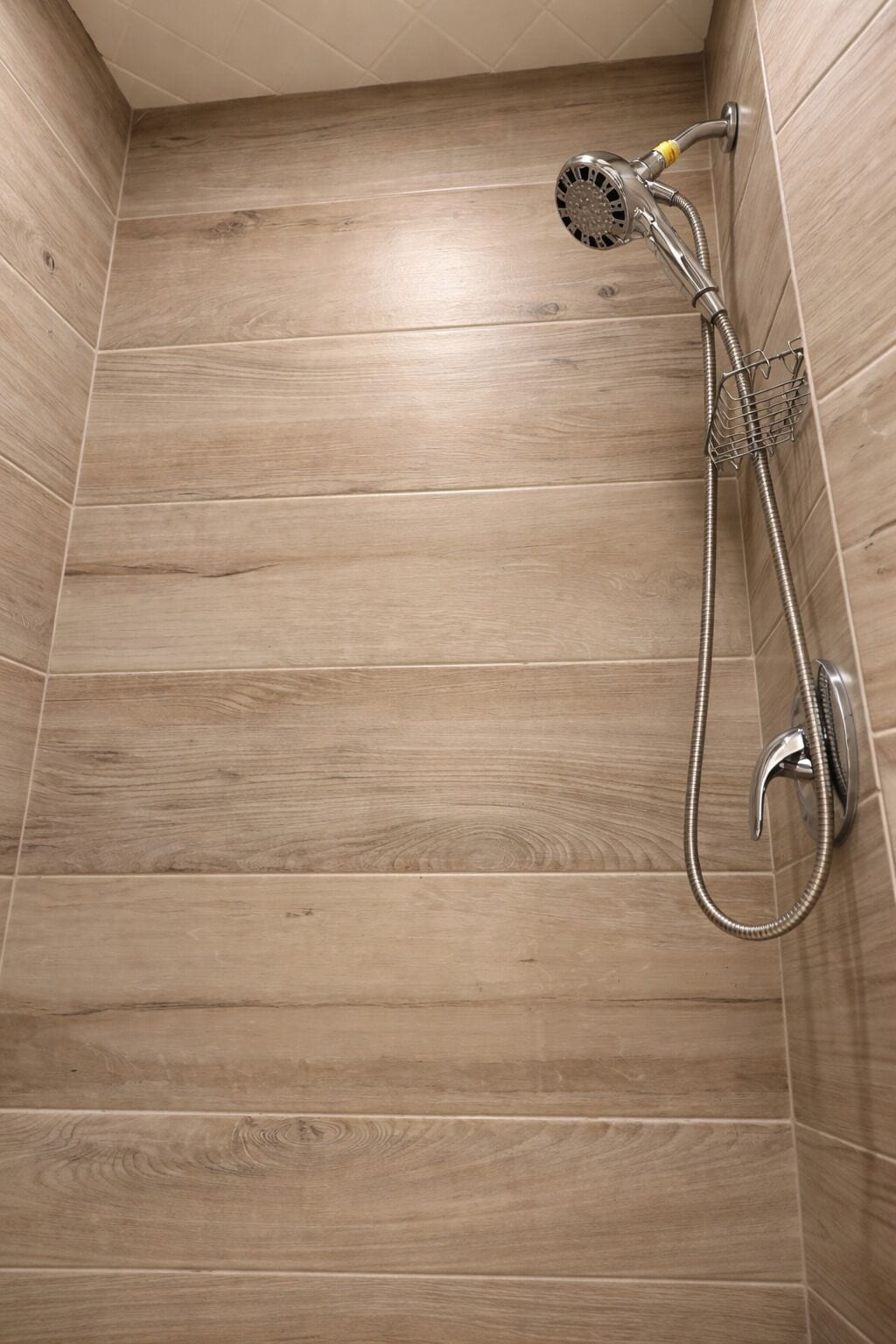 Un área de ducha con pared de madera, ducha de mano y grifo empotrado.