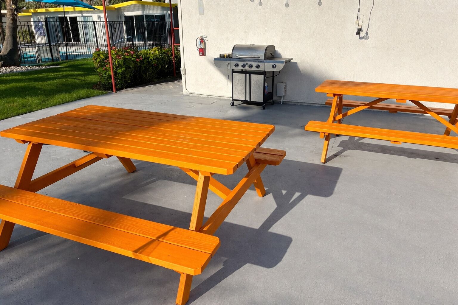 Un patio exterior con mesas de picnic y una parrilla.
