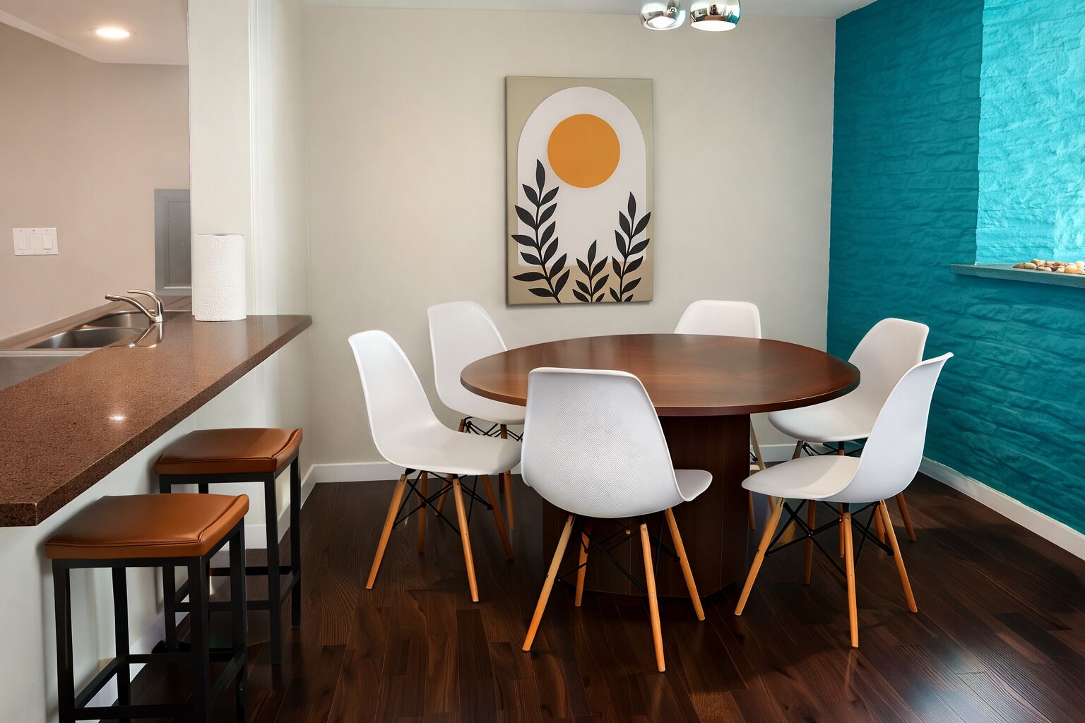 A modern kitchen with a wooden countertop, a round dining table with white chairs, and a wall-mounted artwork.