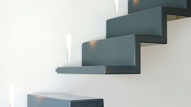 Una escala moderna amb un disseny minimalista, amb graons foscos i il·luminació integrada.