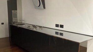 Una cuina moderna amb un taulell negre elegant, un forn integrat i una illa gran amb tapa de vidre.