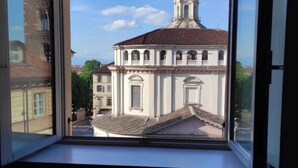 Vista des d'una finestra d'un edifici amb una torre destacada i finestres d'arc.