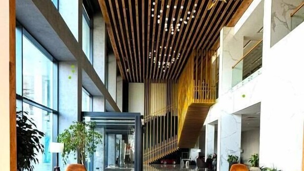 Eine großzügige Lobby mit hoher Decke, moderner Einrichtung und Marmorboden.