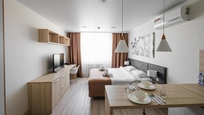 Ein modernes Hotelzimmer mit Bett, Nachttisch, Fernseher, Schreibtisch und Kleiderschrank.