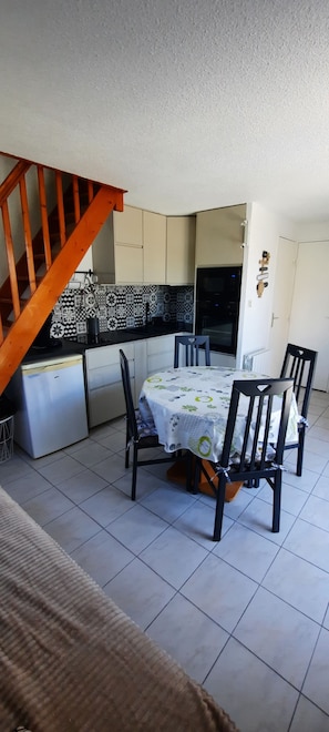 A kitchen with a dining table, chairs, a refrigerator, and a microwave.