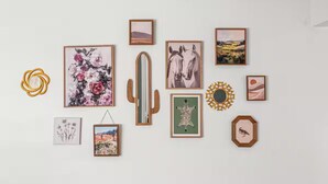 Un mur orné de divers tableaux encadrés, notamment des motifs floraux, des chevaux et des œuvres aux formes abstraites.