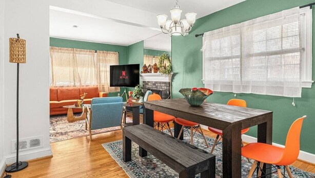 Un salon avec une table à manger en bois, des chaises orange, un canapé bleu et un téléviseur.